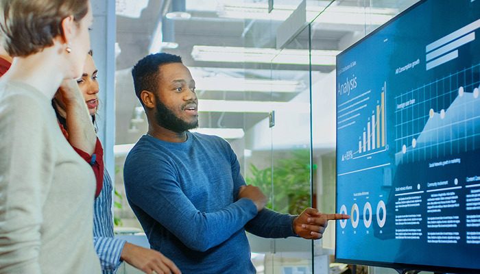 A team looking at data tables on a large screen